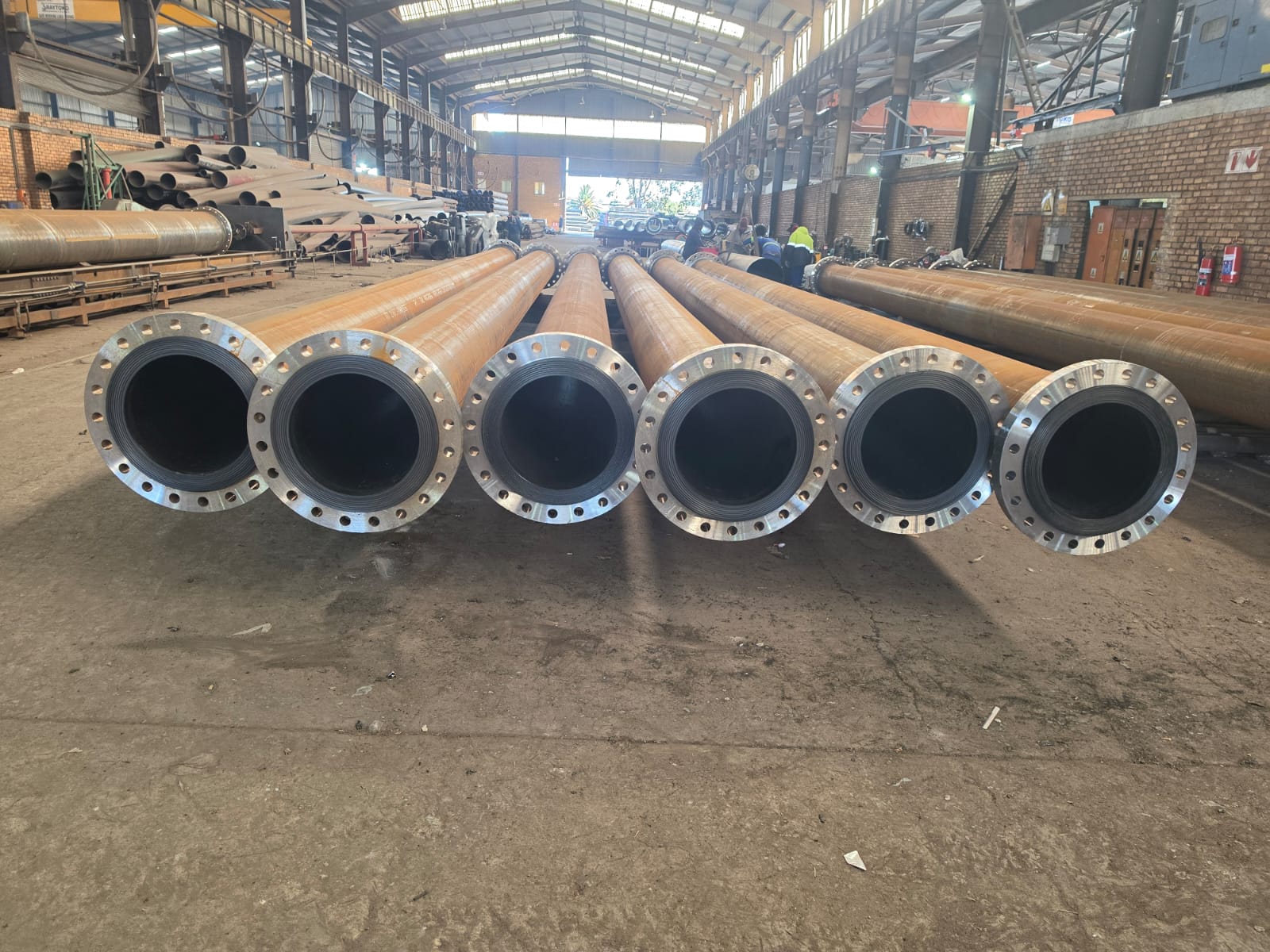 Row of HDPE-lined flanged steel slurry pipes staged in the Wetpipe fabrication workshop